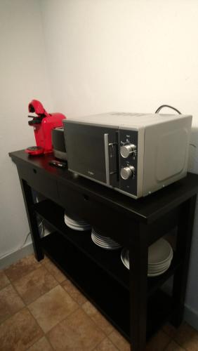 une table noire avec un four micro-ondes et un grille-pain dans l'établissement couette et café Cyrano, à Bergerac