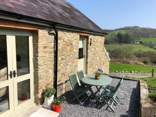 a table and chairs outside of a stone cottage at Danygraig Cottage in Carmarthen