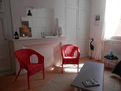 sala de estar con 2 sillas rojas y chimenea en couette et café Cyrano, en Bergerac