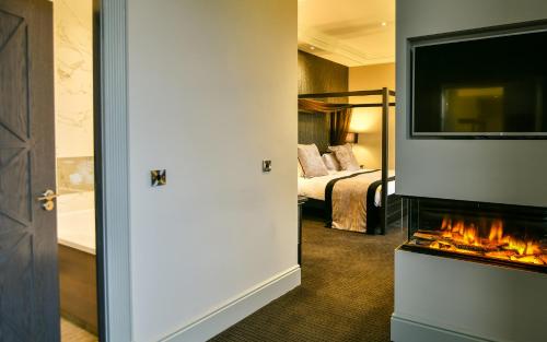 a hotel room with a fireplace and a bed at Hetland Hall Hotel in Dumfries