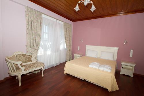 a bedroom with a bed and a chair and a window at Hotel Monodendri in Monodendri