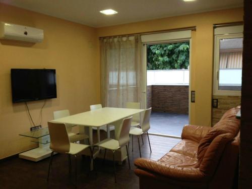 salon ze stołem, krzesłami i telewizorem w obiekcie Apartamento Cala Blanca w mieście Gandía