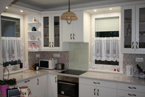 a white kitchen with white cabinets and a microwave at Mona Home in Hévíz