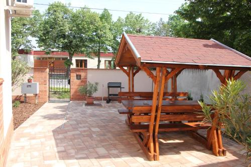 a wooden gazebo with a roof on a patio at Imola és Andrea Apartmanház 2 in Hajdúszoboszló
