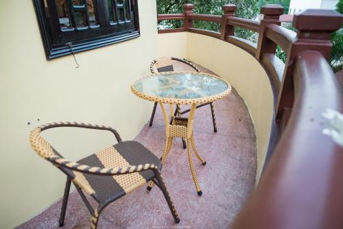 two chairs and a glass table on a balcony at Spring Garden Villa in Hue