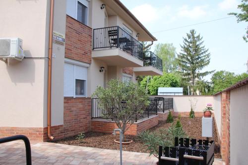 un edificio de apartamentos con balcón y 2 bancos en Imola és Andrea Apartmanház 2, en Hajdúszoboszló