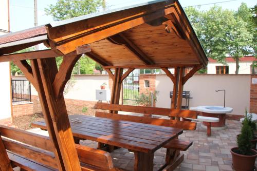 a wooden gazebo with a bench on a patio at Imola és Andrea Apartmanház 2 in Hajdúszoboszló