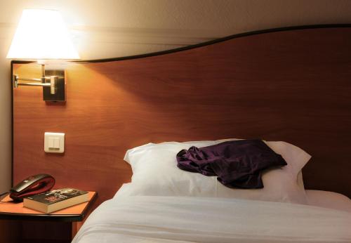 a bedroom with a bed and a lamp and a book at Hotel Eden Montmartre in Paris