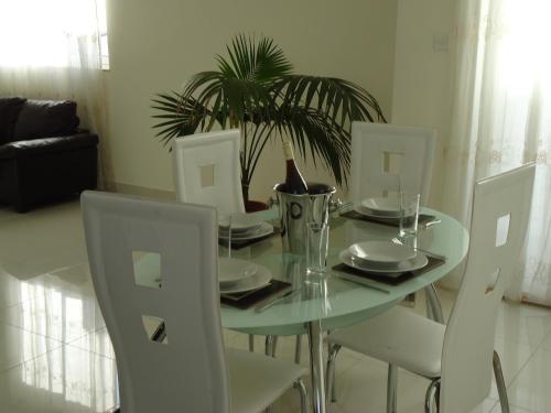 a dining room table with white chairs and a plant at Shamrock Flats in Mellieħa