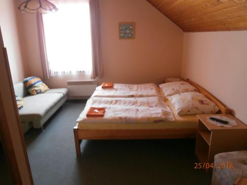 a bedroom with a bed and a couch and a window at Penzion Oliver in Horní Planá