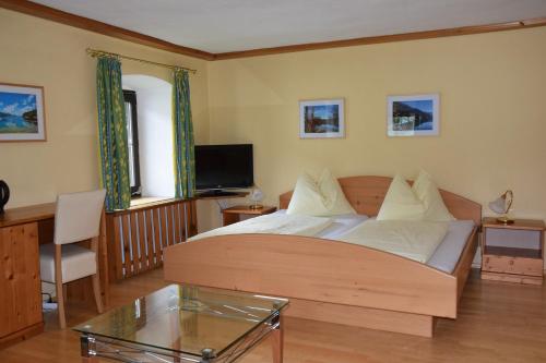 a bedroom with a bed and a desk and a tv at Pension Hohenau in Fuschl am See
