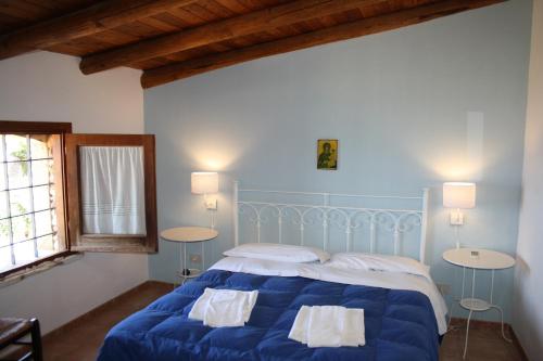 una camera con un letto blu con due tavoli di Casale Corcella a Scopello