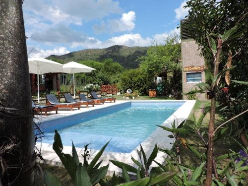 ein Swimmingpool mit Stühlen und Sonnenschirmen in der Unterkunft CABAÑAS LOS COCKERS in Villa General Belgrano