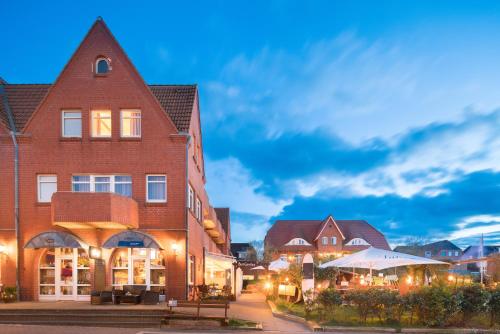 een stadsstraat met een gebouw en tafels en een gebouw bij Seeblick Genuss und Spa Resort Amrum in Norddorf