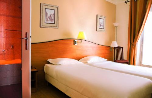 a hotel room with two beds and a window at Hotel Eden Montmartre in Paris