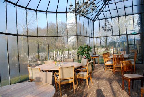 a dining room with tables and chairs in a greenhouse at Orshof in Oudsbergen 