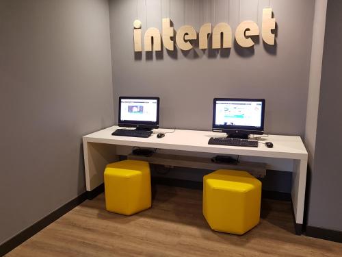 two computers on a white desk with yellow stools at ibis budget Sao Paulo Morumbi in Sao Paulo