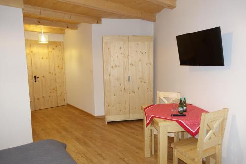 a dining room with a red table and chairs and a television at Willa Zaolzie in Istebna