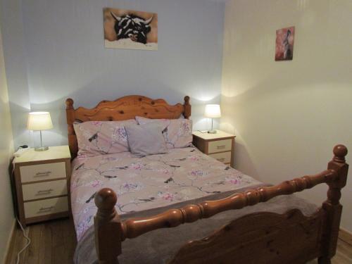 1 dormitorio con 1 cama de madera y 2 mesitas de noche en Farraline Court en Inverness