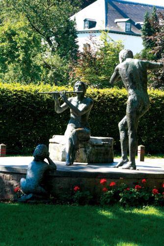 a statue of two people sitting in a park at Fletcher Hotel La Ville Blanche in Thorn