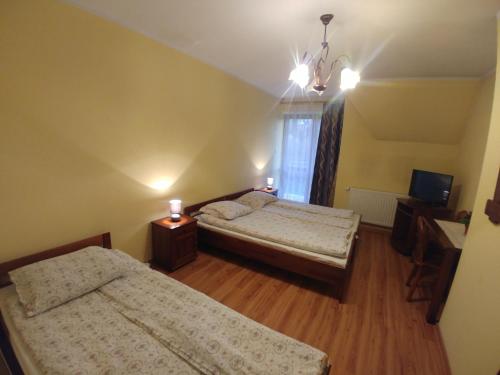 a bedroom with two beds and a television in it at Willa Pawlikowskich in Poronin