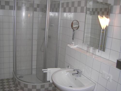 a bathroom with a shower and a sink and a mirror at AKZENT Hotel Landgasthof Murrer in Straubing