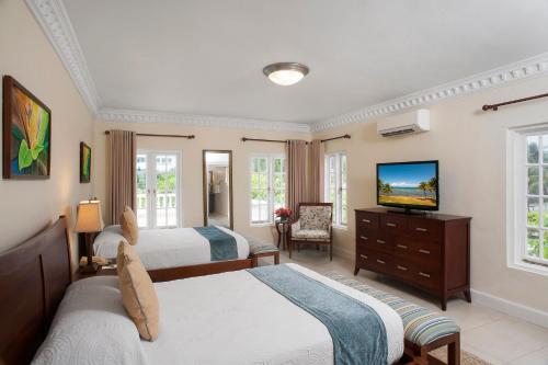 a bedroom with two beds and a flat screen tv at Half Moon in Montego Bay