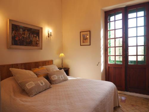 une chambre avec un lit avec des draps blancs et une fenêtre dans l'établissement Lourmarin,Domaine de Casteuse Appartement LES OLIVIERS, à Lourmarin