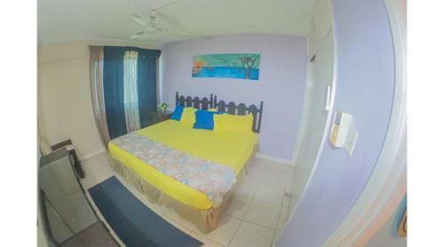 ein Schlafzimmer mit einem gelben Bett mit blauen Kissen in der Unterkunft Sword Fish Beach Suite@ Turtle Towers in Ocho Rios