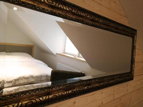 a mirror in a room with a bed and a window at Kamienica Na Nowo Apartamenty in Mrągowo