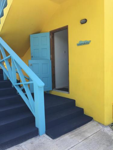 a stairway with a yellow wall and a blue door at CasaCalypso Grenada in Belmont