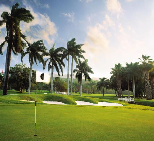 a golf course with palm trees and a putting green at Half Moon in Montego Bay