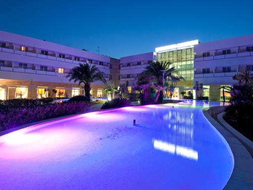 a large swimming pool in front of a building at night at Regiohotel Manfredi in Manfredonia