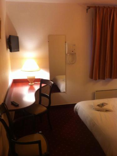 a hotel room with a desk and a bed at Hotel Couleurs Sud Centre-ville Gare Charleville-Mézières in Charleville-Mézières