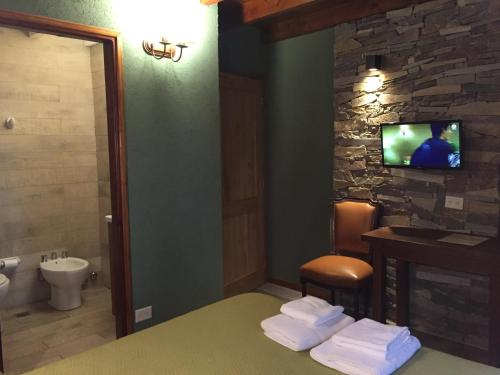 a bathroom with a toilet and a tv on a wall at Hostería Las Cumbres in Villa La Angostura