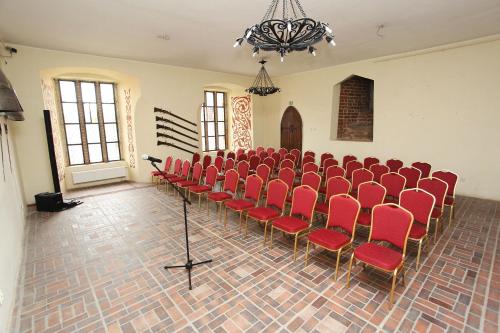 an empty room with red chairs and a chandelier at Zamek Gniew - Pałac Marysieńki in Gniew