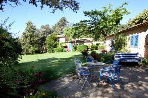 a patio with chairs and a table in a yard at La Ferme in Saint-Marc-Jaumegarde