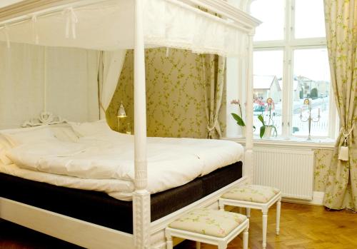 a bedroom with a canopy bed with two chairs at Annas Hotell in Kristianstad