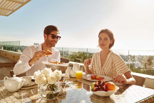 
a man and woman sitting at a table eating food at El Embajador, a Royal Hideaway Hotel "Newly Renovated" in Santo Domingo
