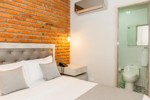 a bedroom with a brick wall and a white bed at Hotel Boutique ADAZ in Santa Marta
