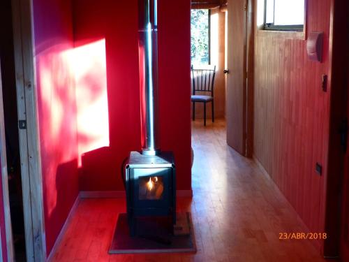a stove in a room with a red wall at Cabañas Latitud 41 Sur in Quillaipe