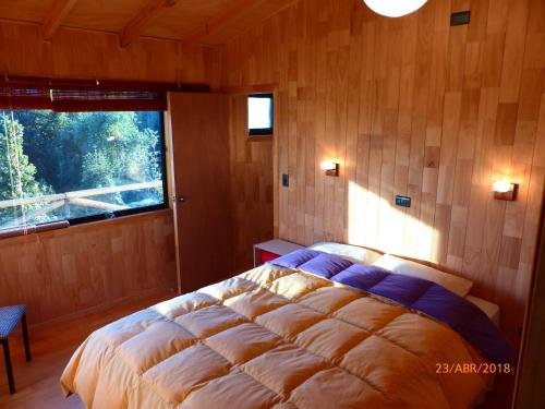 a bedroom with a bed in a room with a window at Cabañas Latitud 41 Sur in Quillaipe