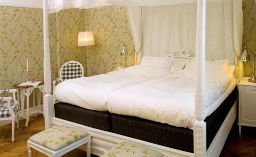 a bedroom with a white canopy bed with a chair at Annas Hotell in Kristianstad