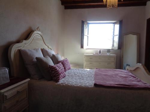 a bedroom with a bed with pillows and a window at Sossego in Pedrógão Grande