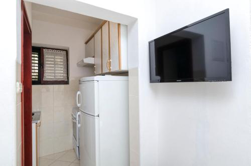 a kitchen with a refrigerator and a tv on a wall at Apartments Mime in Pirovac