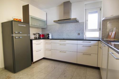 a kitchen with a stainless steel refrigerator and white cabinets at Rust-Fewo-Hotel in Rust