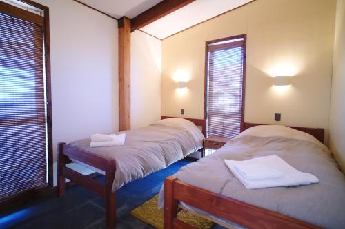 two beds in a room with two windows at Arenaguas Beach House in Matanzas