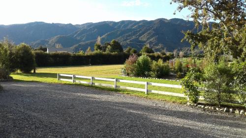 a fence on the side of a road with mountains in the background at Abel Tasman Haven in Marahau