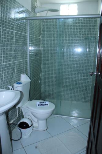 a bathroom with a toilet and a glass shower at Pousada Beijos y Abraços in Natal