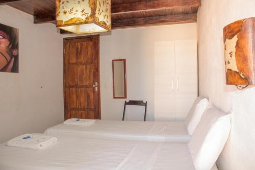 a bedroom with two white beds and a chandelier at Pousada Beijos y Abraços in Natal